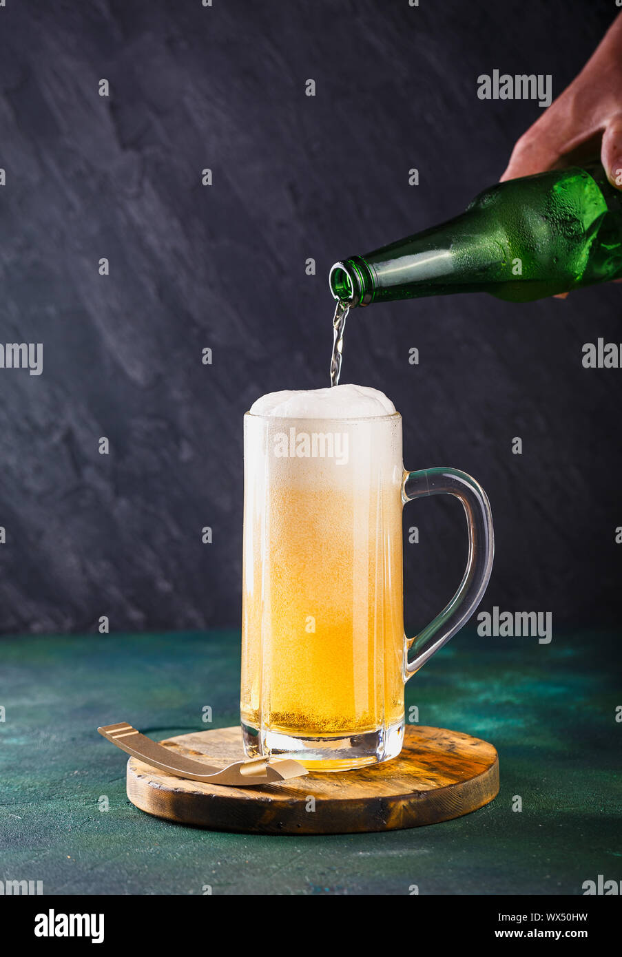 Glass mug with beer with foam and water drops on a dark green background Stock Photo