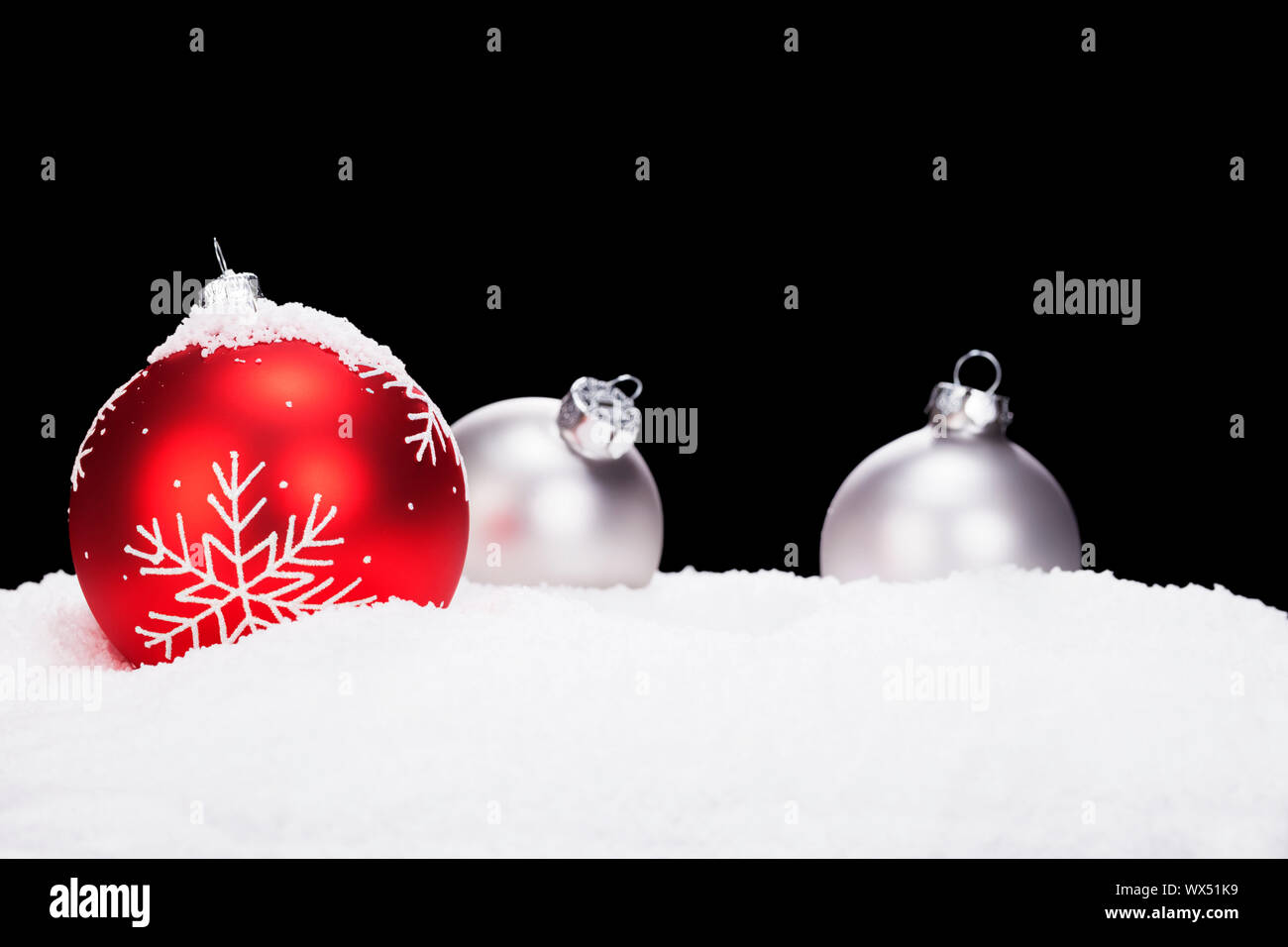 red christmas ball in front of silver christmas balls in snow with ...