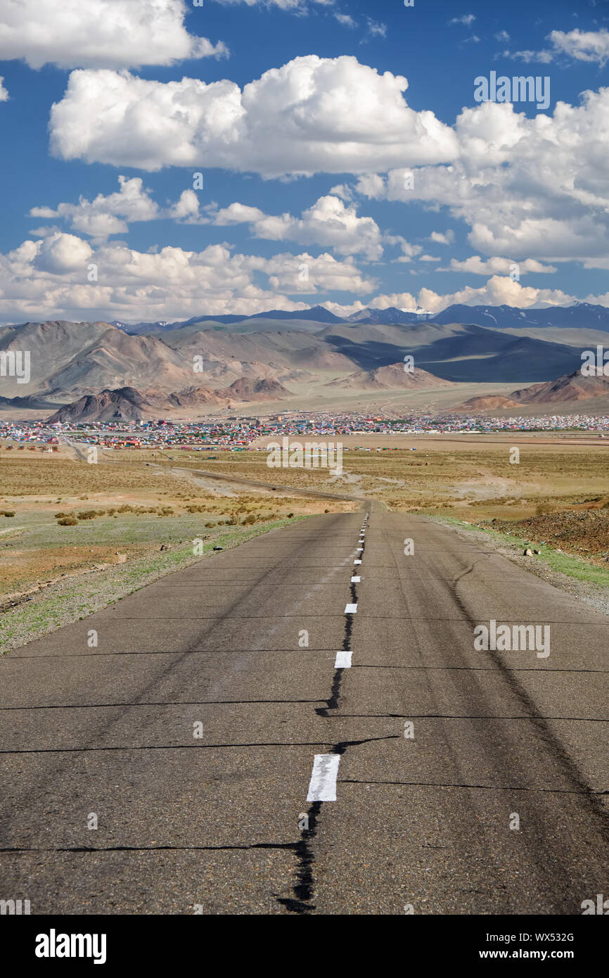 Empty Asphalt road in Mongolia  with mongolian town Bayan-Olgii (Bayan-Ulgii or Ulgii) on background Stock Photo