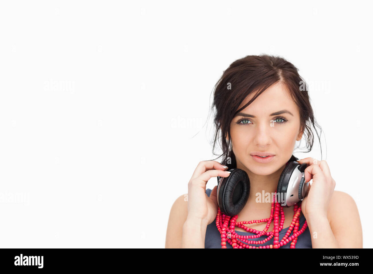 beautiful student with headphones around her neck against white