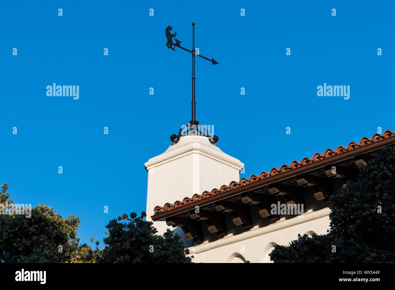 Weather vane on top of a white Spanish Colonial Revival architecture style building with a red tile roof - Santa Barbara, California Stock Photo