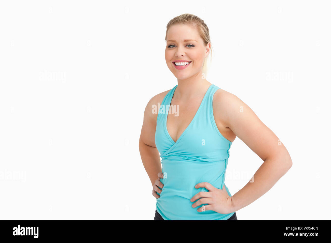 Woman standing with her hands on her hips against white background ...