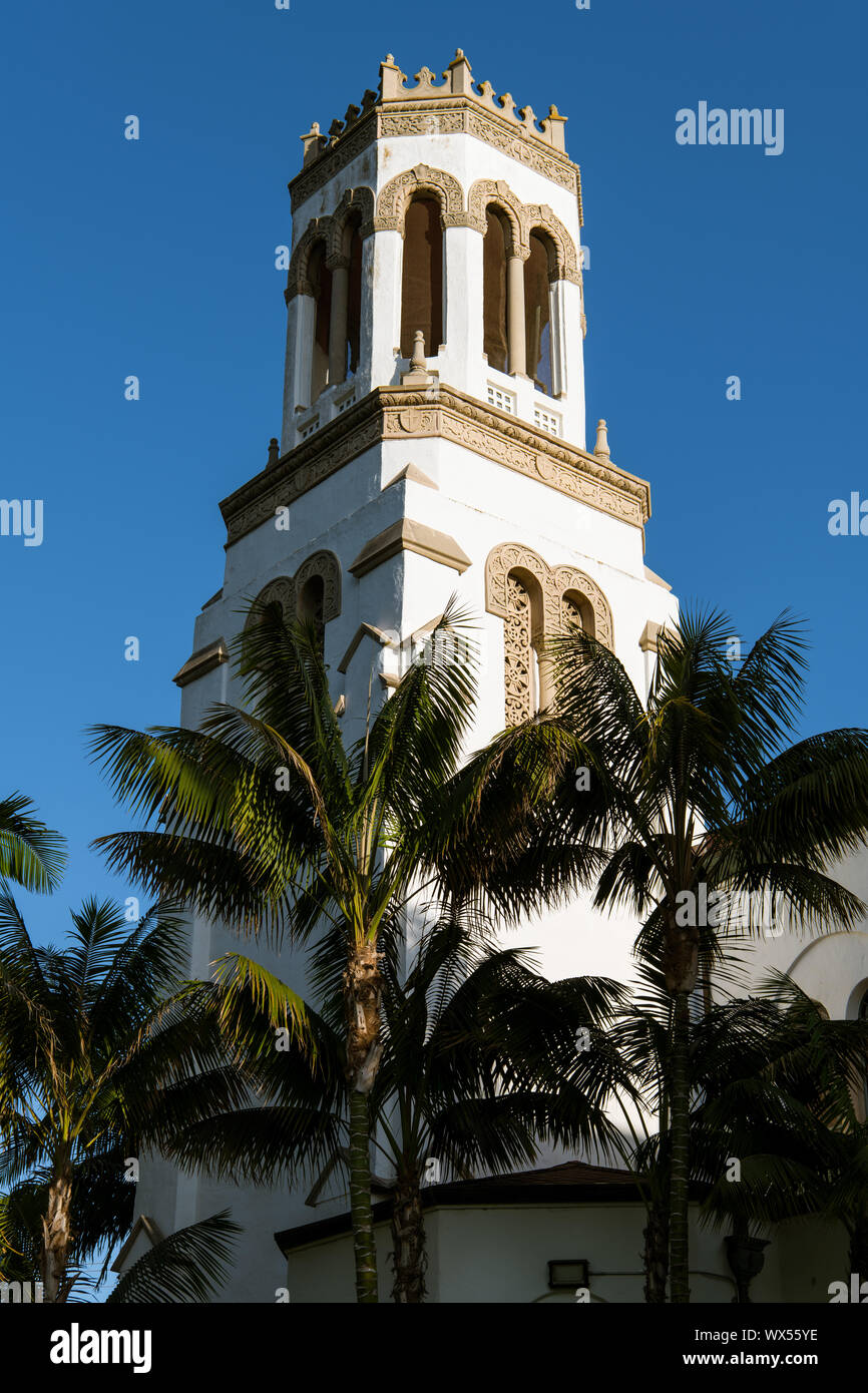 The setting sun highlights one side of a white bell tower and palm trees - Our Lady of Sorrows Church in Santa Barbara, California Stock Photo