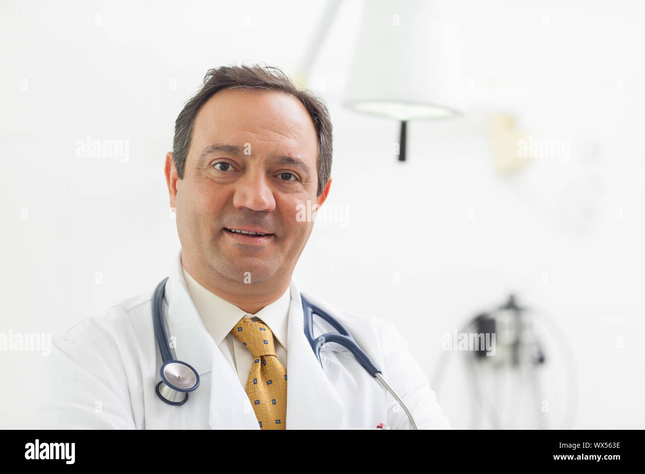 Doctor smiling with a stethoscope around his neck in an examination