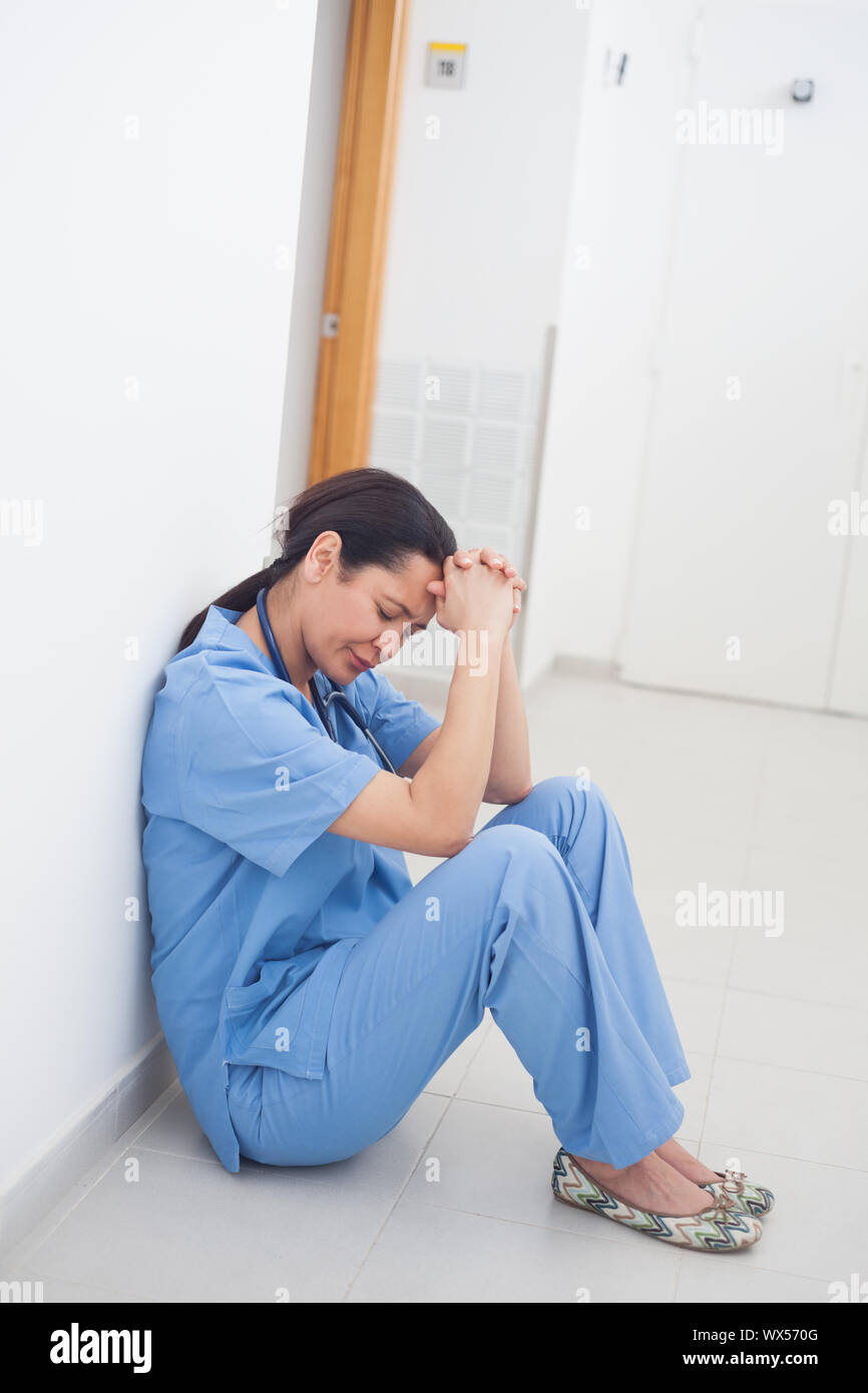 Sad Nurse Sitting On The Floor In Hospital Ward Stock Photo