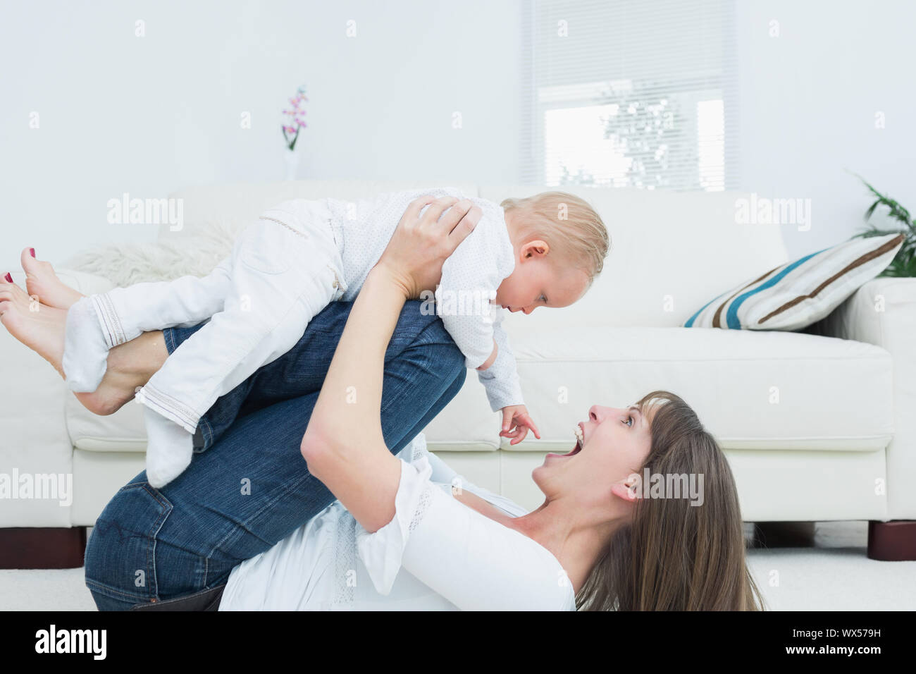 Mother lying playing with a baby in living room Stock Photo Alamy