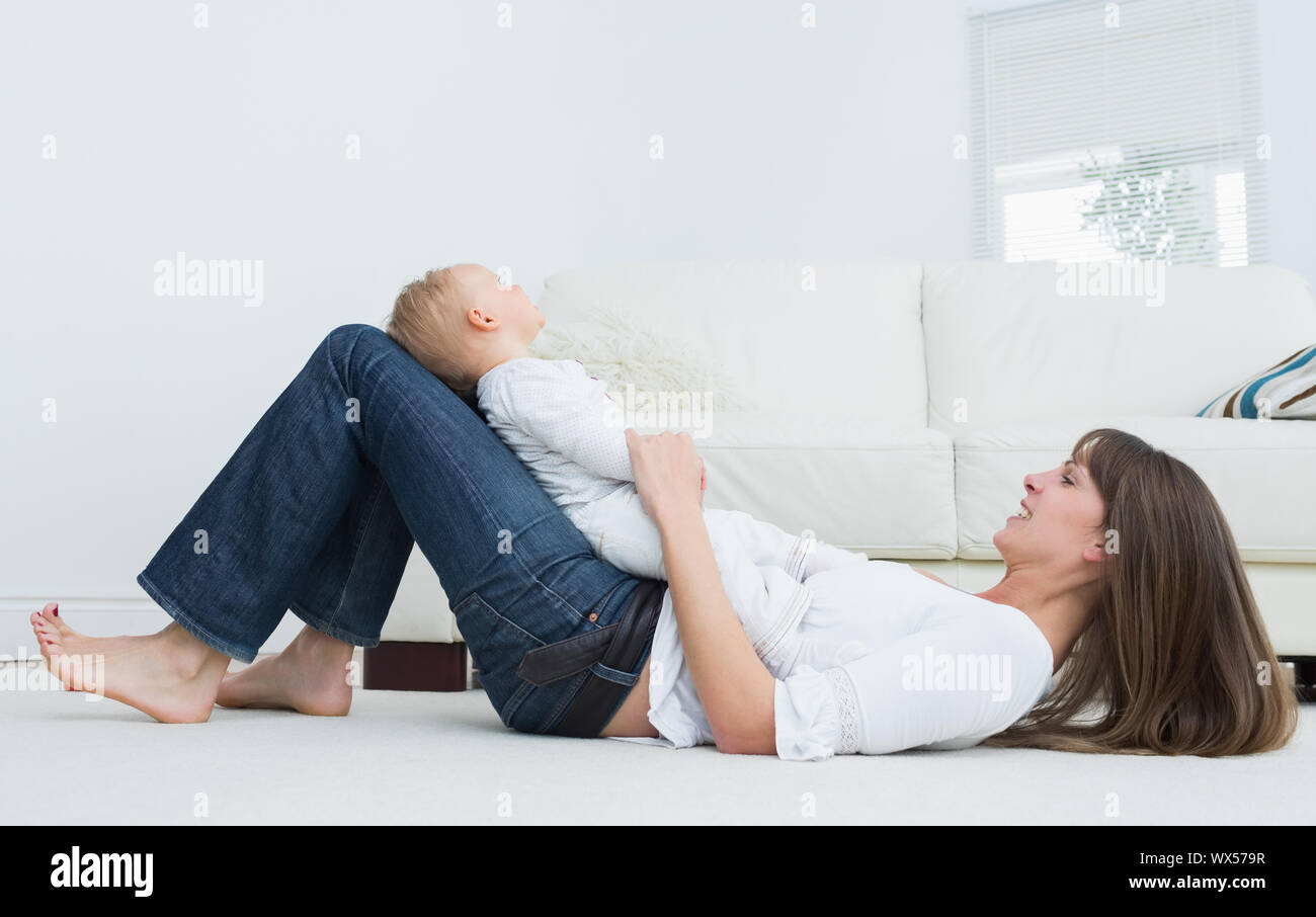 Mother lying on the floor with a baby in living room Stock Photo Alamy