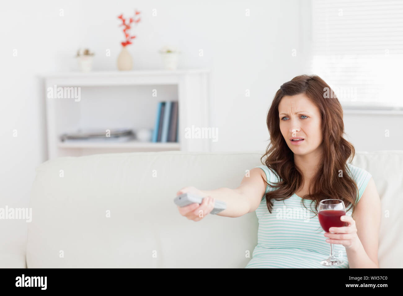 Woman sitting on a sofa while holding a glass of wine in a living room Stock Photo