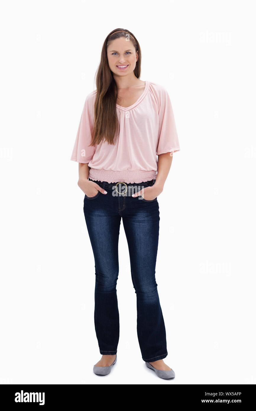 Woman smiling with her hands in her pockets against white background ...
