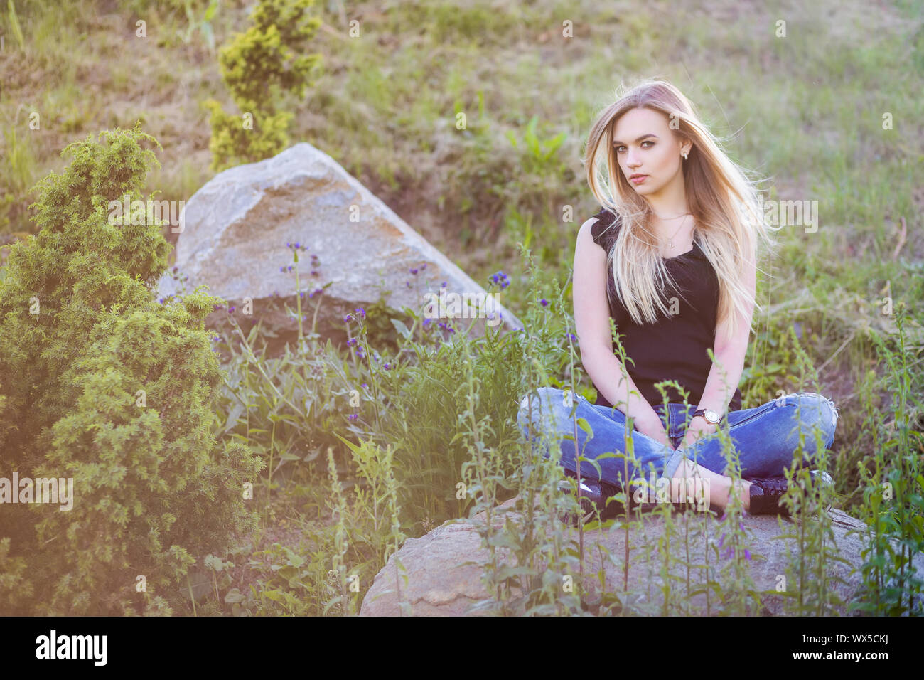 Pensive woman posing sitting on a stone. Stock Photo
