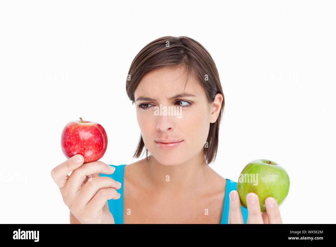 Teenage looking at the red apple while also holding a green one Stock