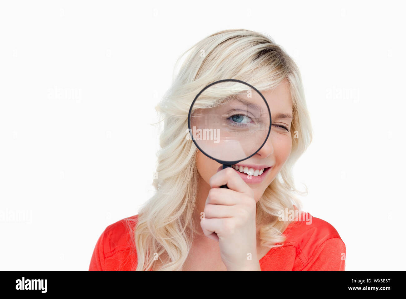 Woman looking through a magnifying glass while showing a blink of an