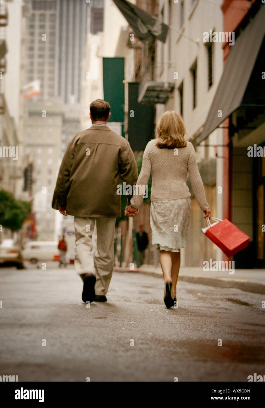 Couple walking down city street holding hands Stock Photo - Alamy