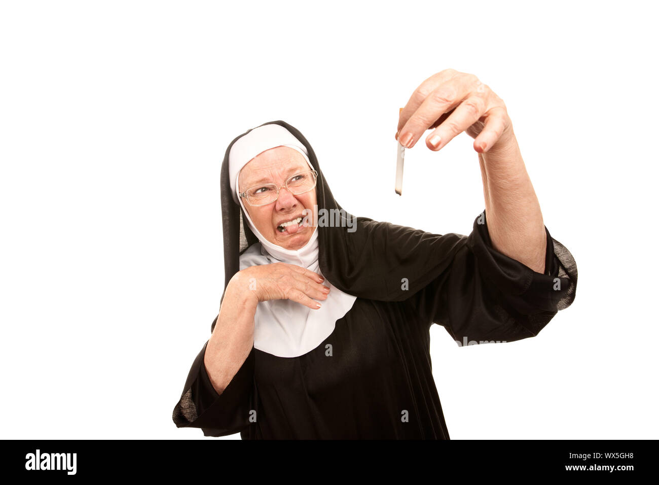 Senior nun showing disgust holding burnt cigarette Stock Photo