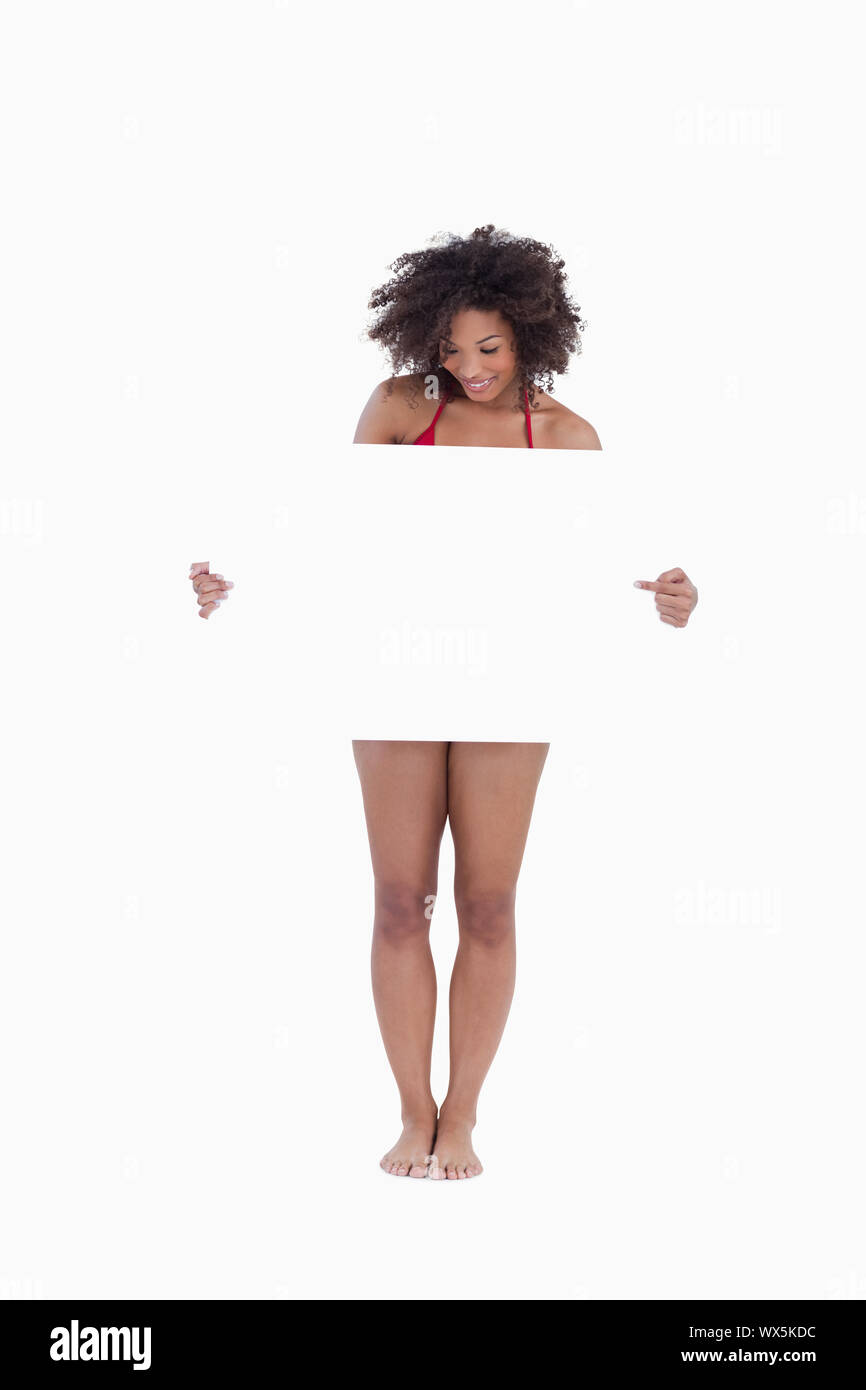 Woman looking down while pointing a blank poster against a white background Stock Photo