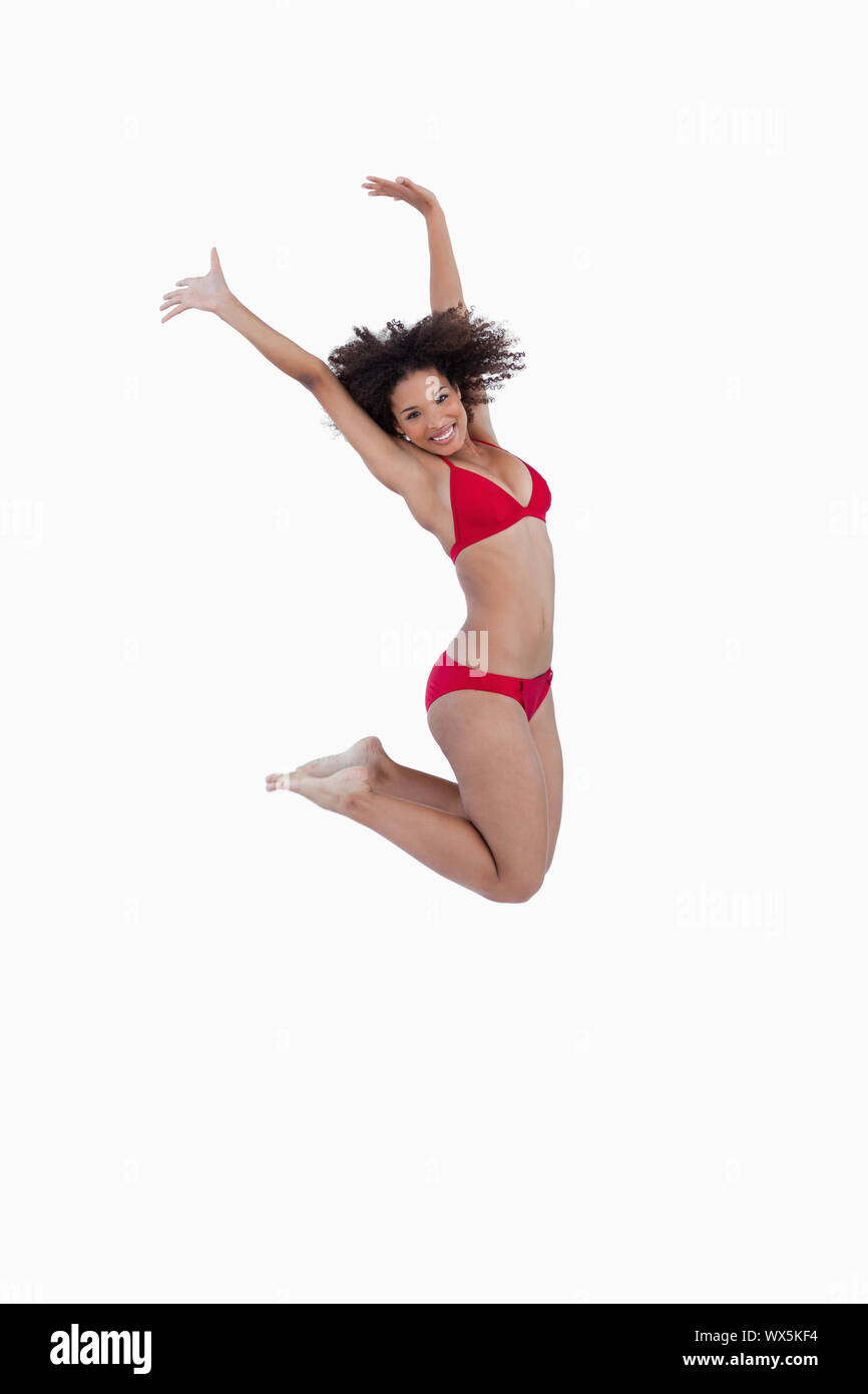 Side view of a young woman jumping against a white background Stock Photo