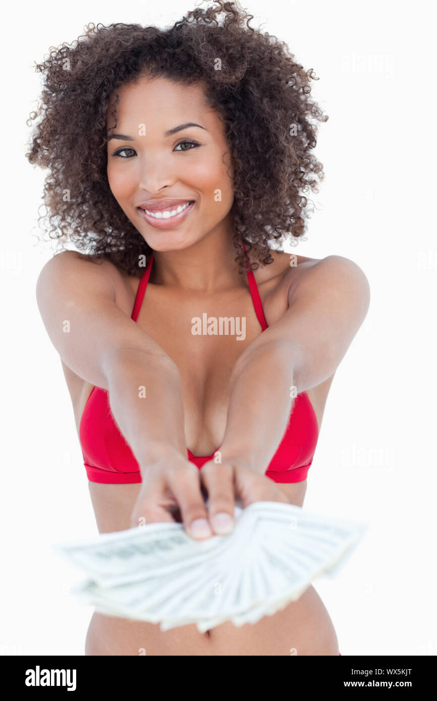 Smiling brunette woman standing upright while holding a fan of dollar notes Stock Photo