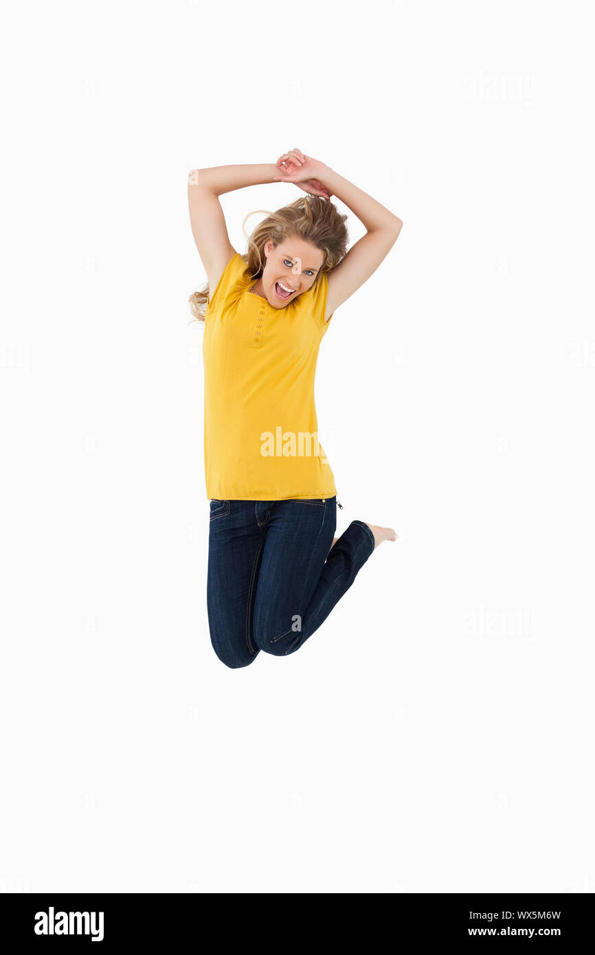 Young woman in yellow shirt jumping against white background Stock ...