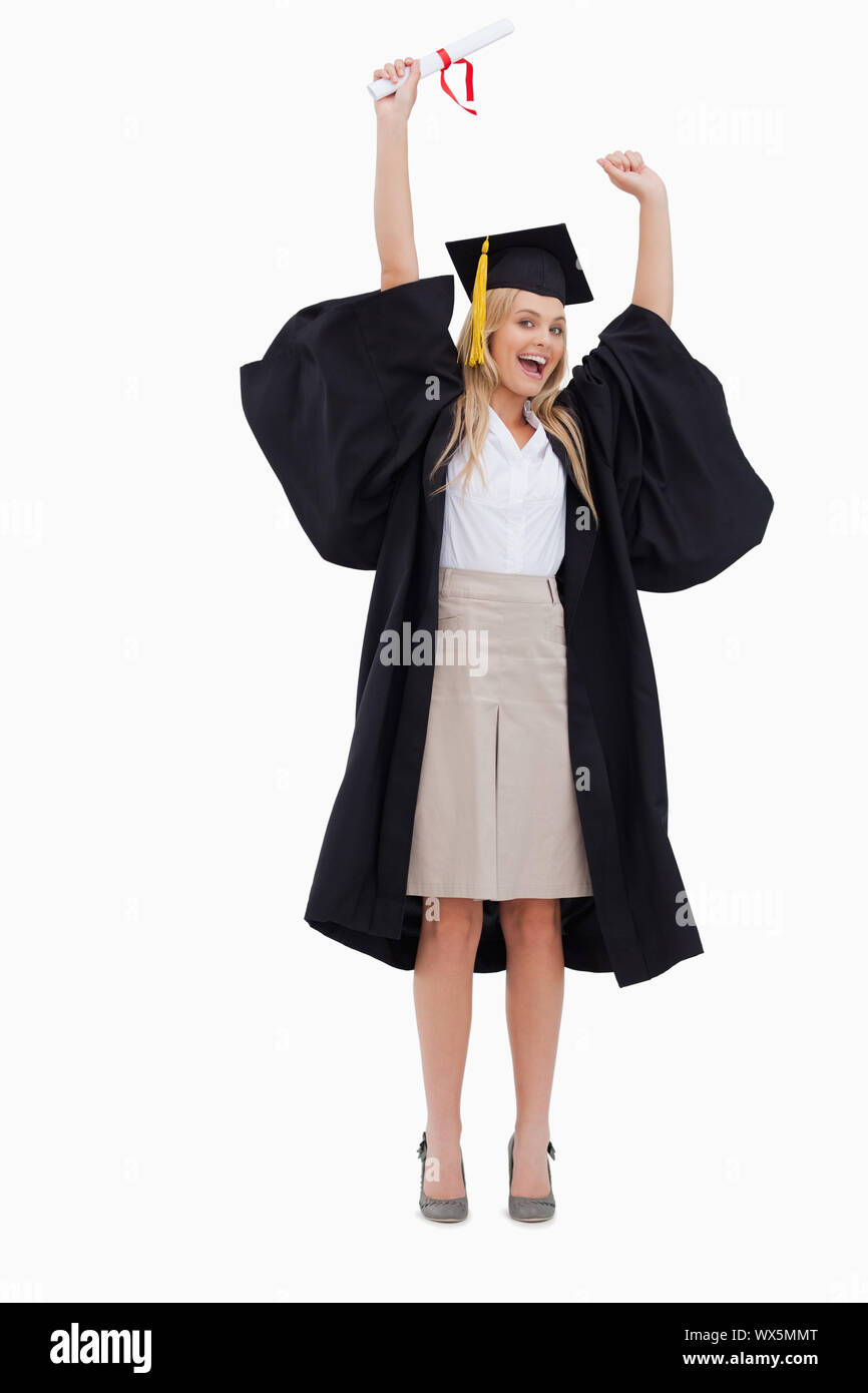 Blonde student in graduate robe holding up her diploma against white ...