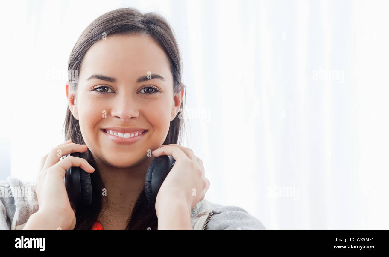 A woman looking into the camera and smiling while wearing headphones