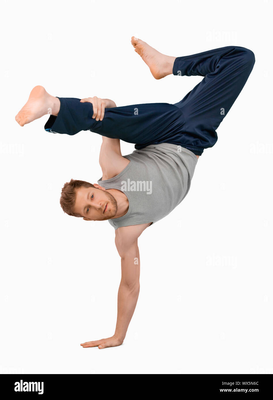 Break dancer doing an one handed handstand against a white background Stock Photo