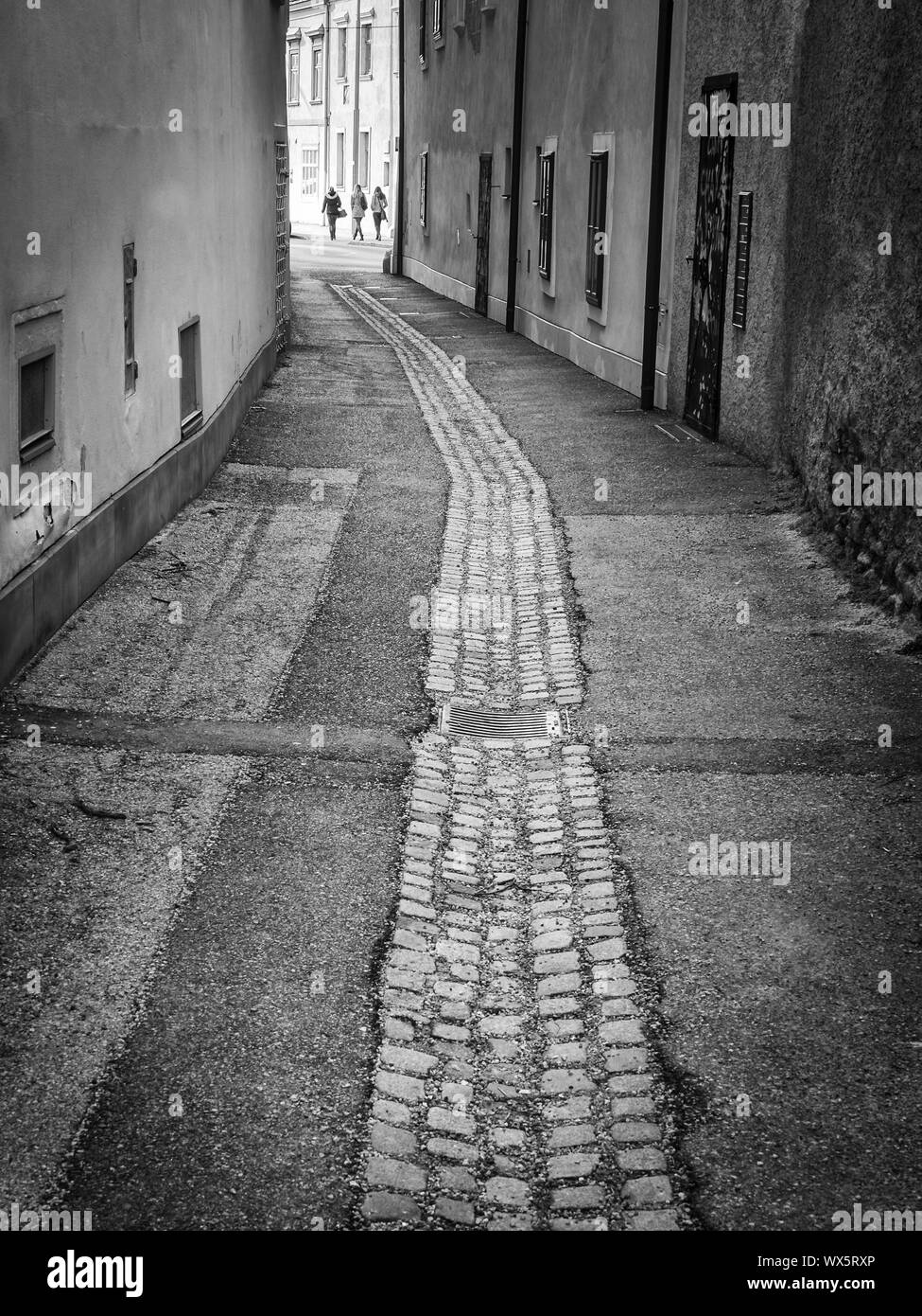 Narrow old stret with three girls in the distance Stock Photo