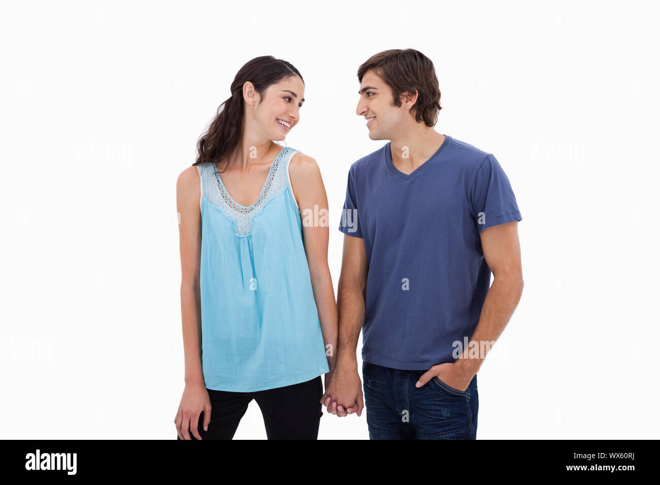 Young couple holding hands against a white background Stock Photo - Alamy