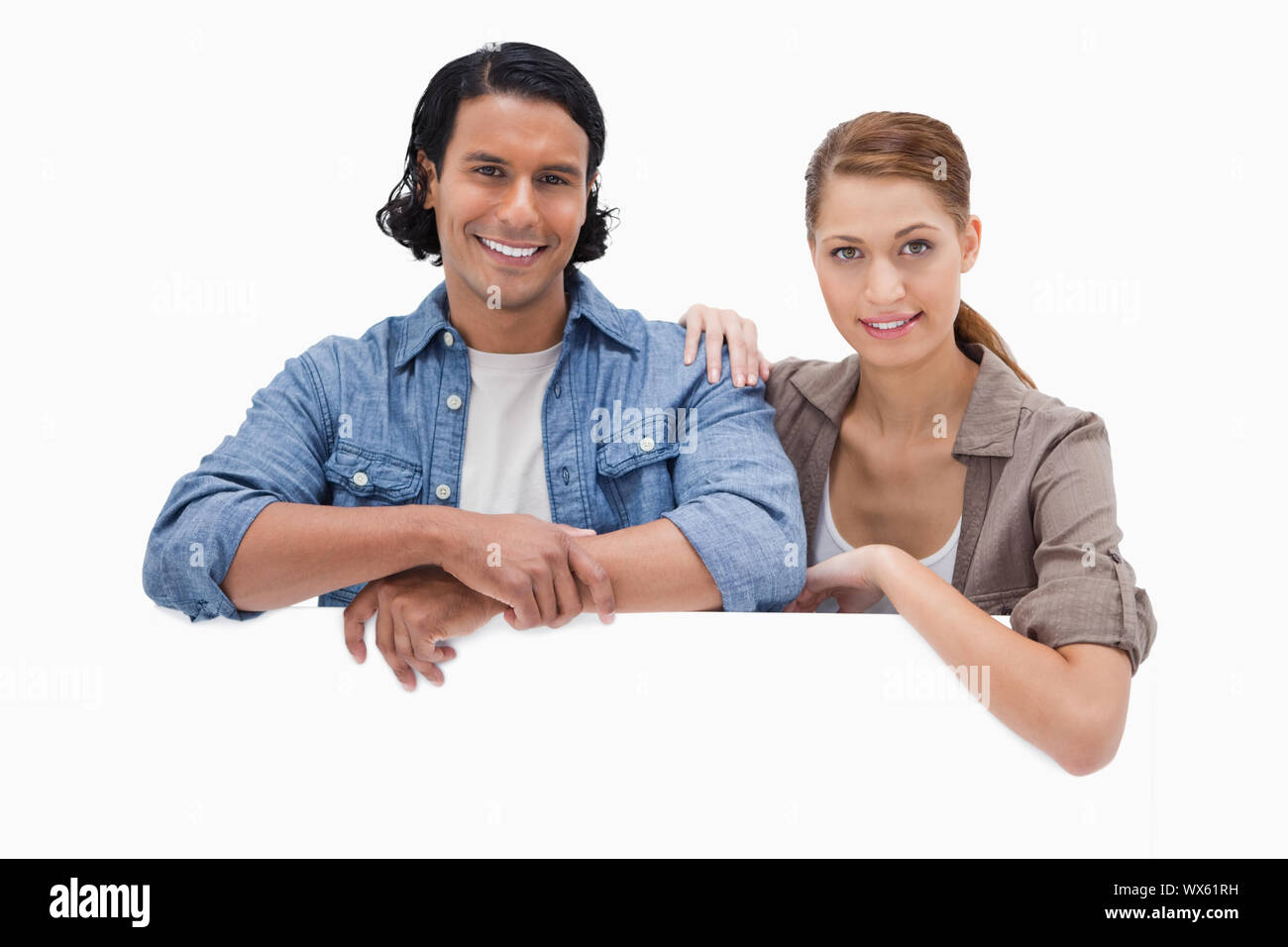 Couple leaning on blank wall against a white background Stock Photo
