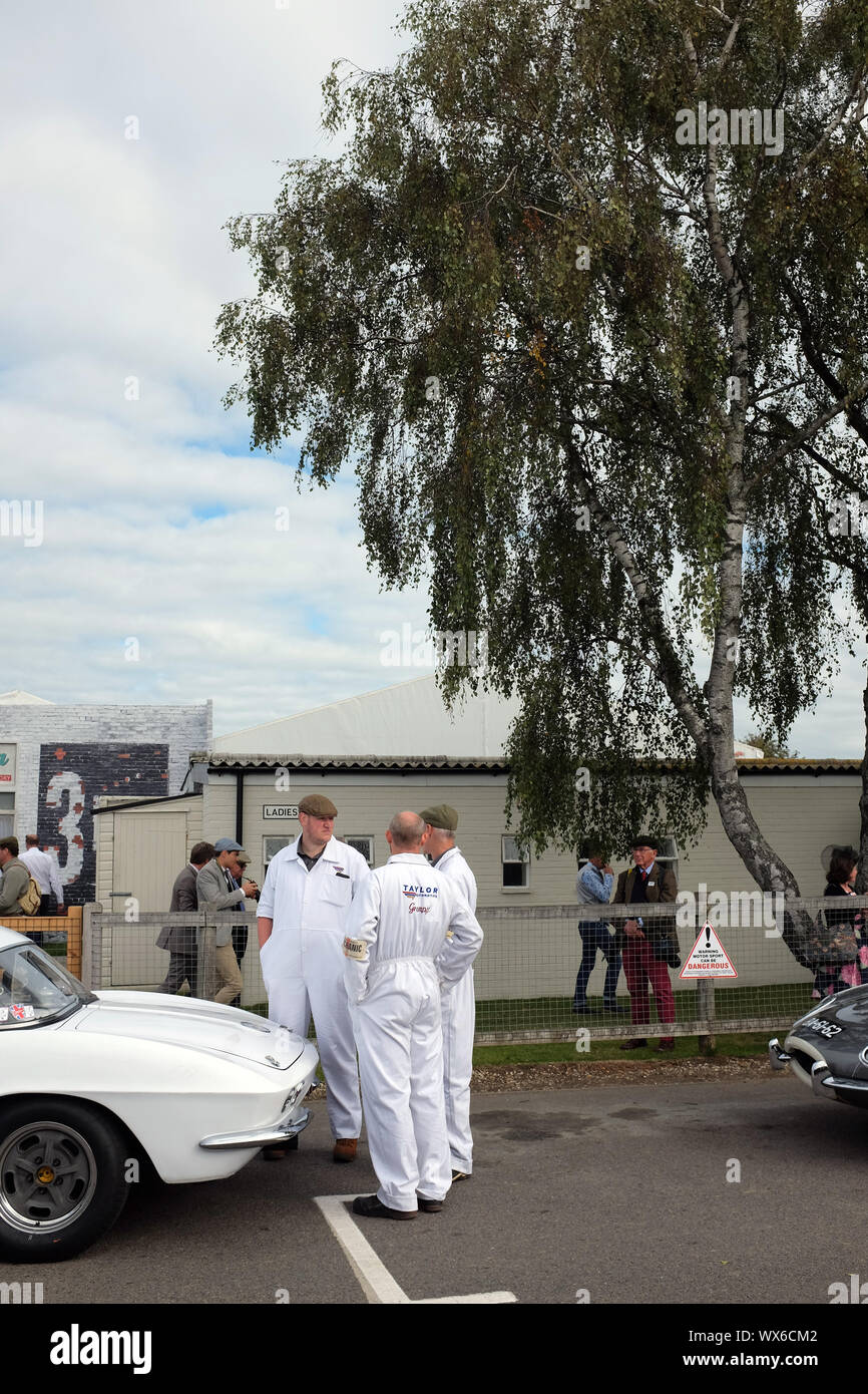 September 2019 - Group of mechanics in White overalls talking at the back  of a white classic race car at the Goodwood Revival Stock Photo - Alamy