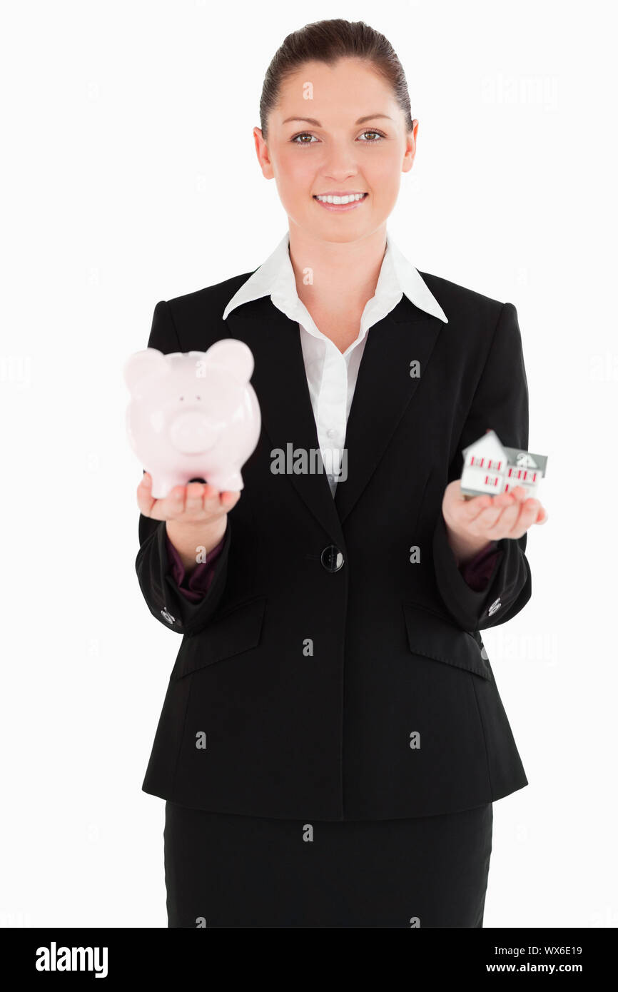 Attractive woman in suit holding a piggy bank and a miniature house ...