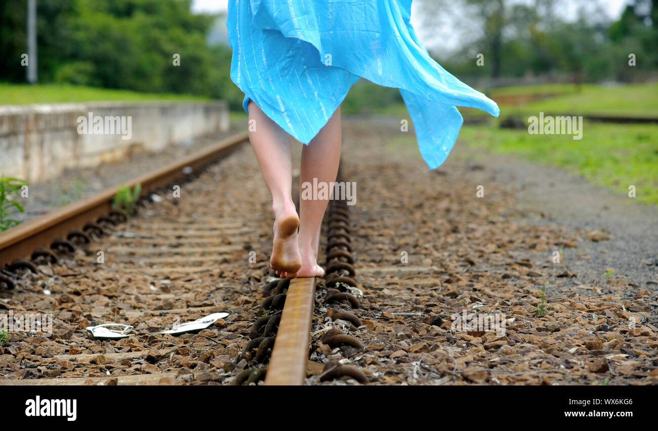 She leaves her shoes behind and balances along the tracks Stock Photo