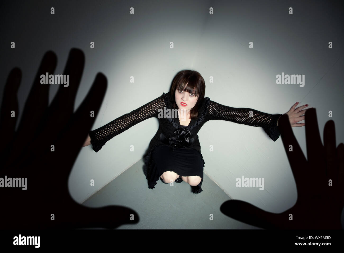 Young horror victim being menaced in corner Stock Photo - Alamy