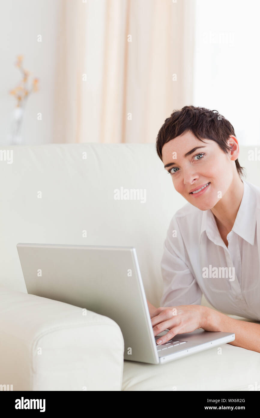 Cute Woman lying on a sofa with a laptop in the living room Stock Photo ...