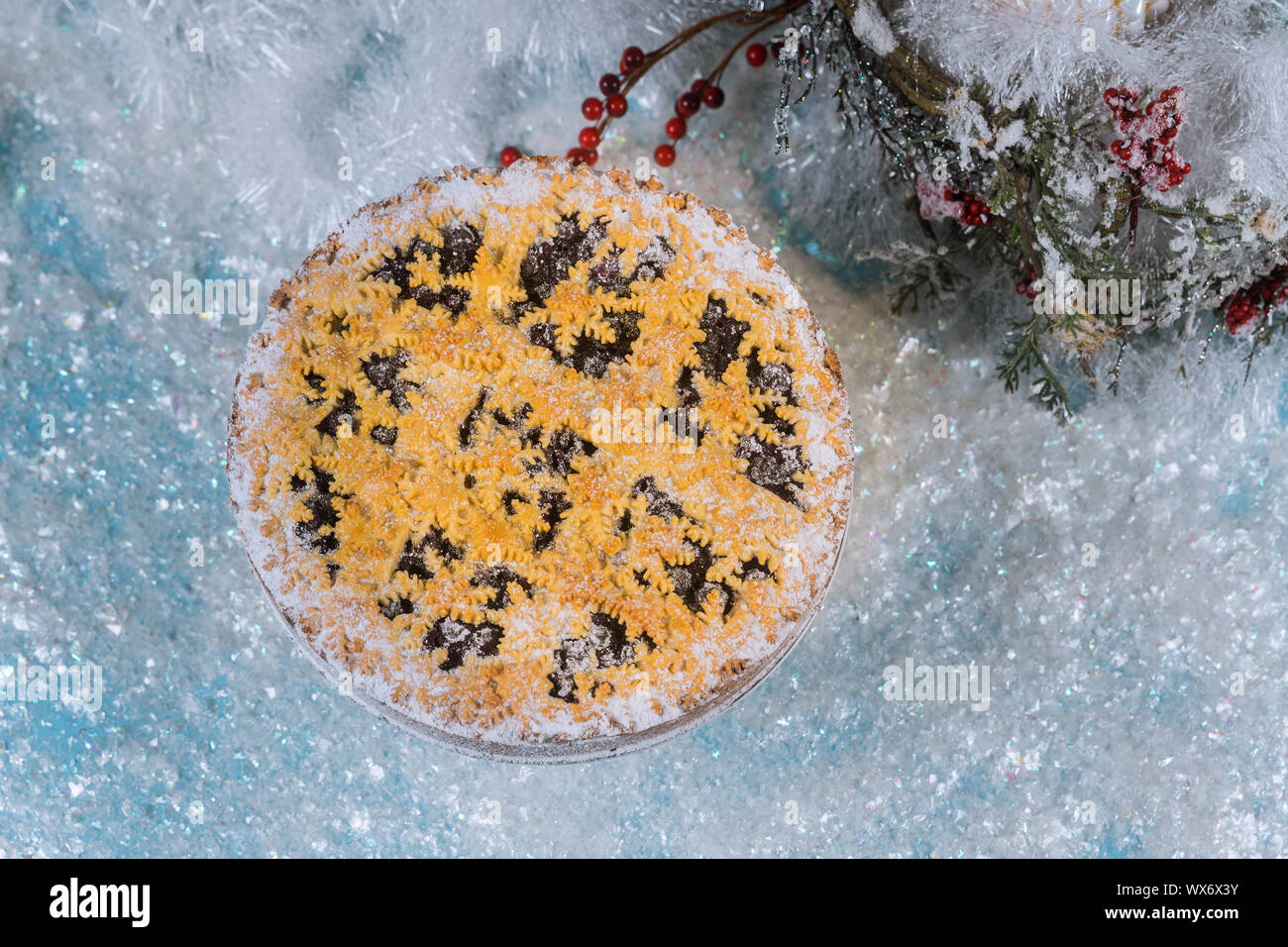 Christmas pie and decorations on sparkle snow background. Stock Photo