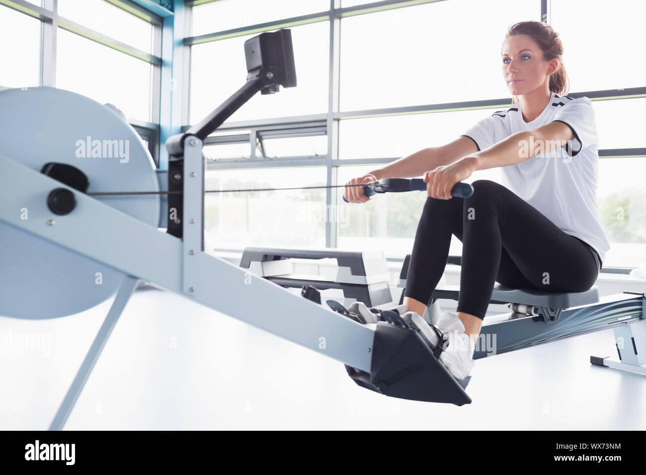 Concetrating woman training on row machine in gym Stock Photo