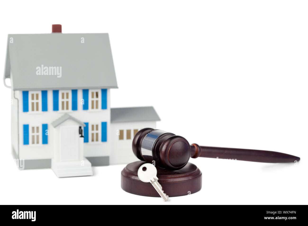 Grey toy house model with a key and a brown gavel against a white