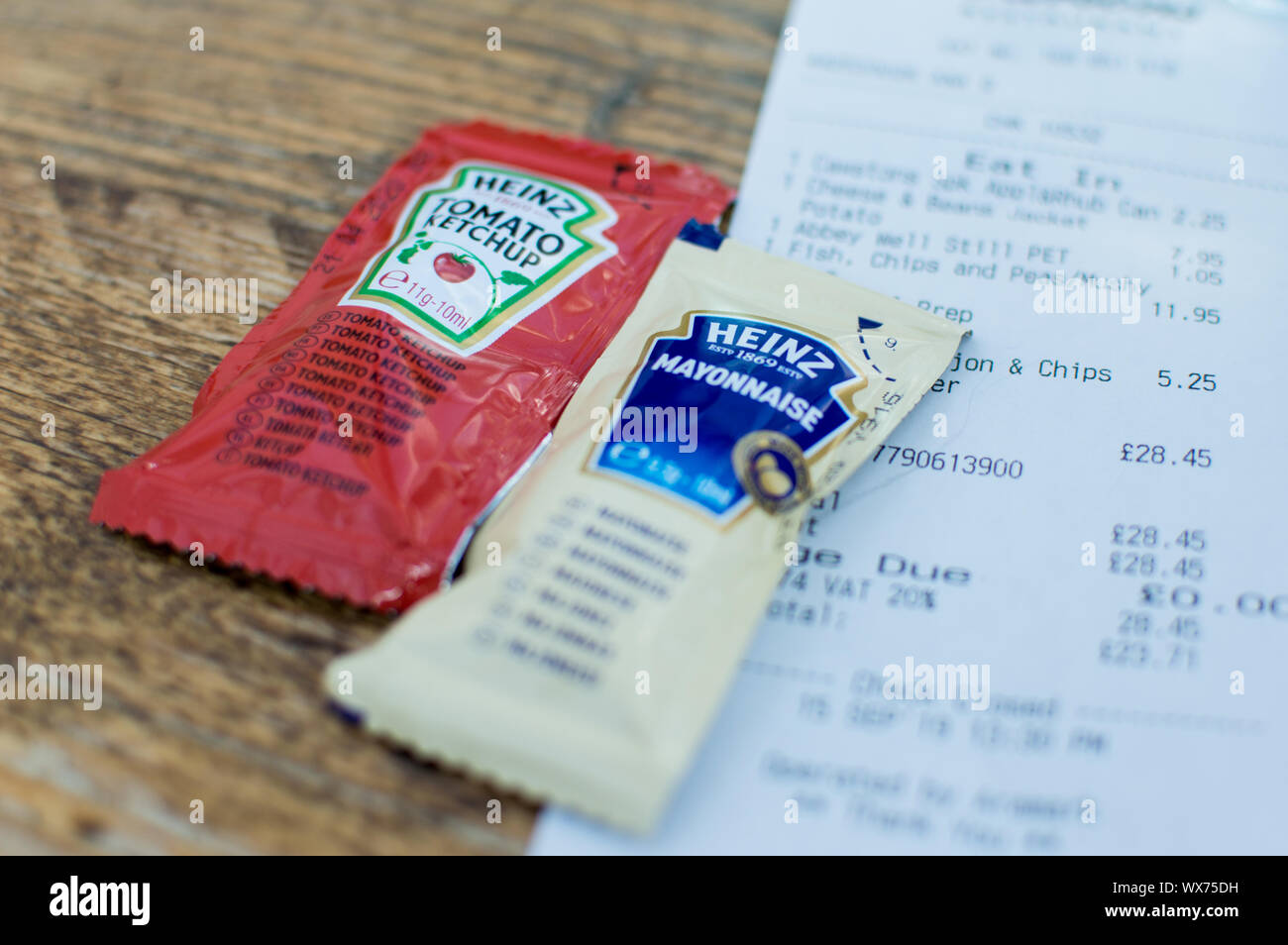 Heinz ketchup and HP Brown sauce on a wooden table next to a restaurant bill Stock Photo