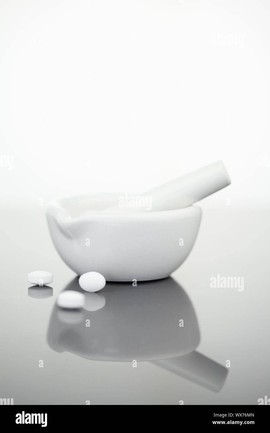 Mortar and pestle with pills against a white background Stock Photo - Alamy