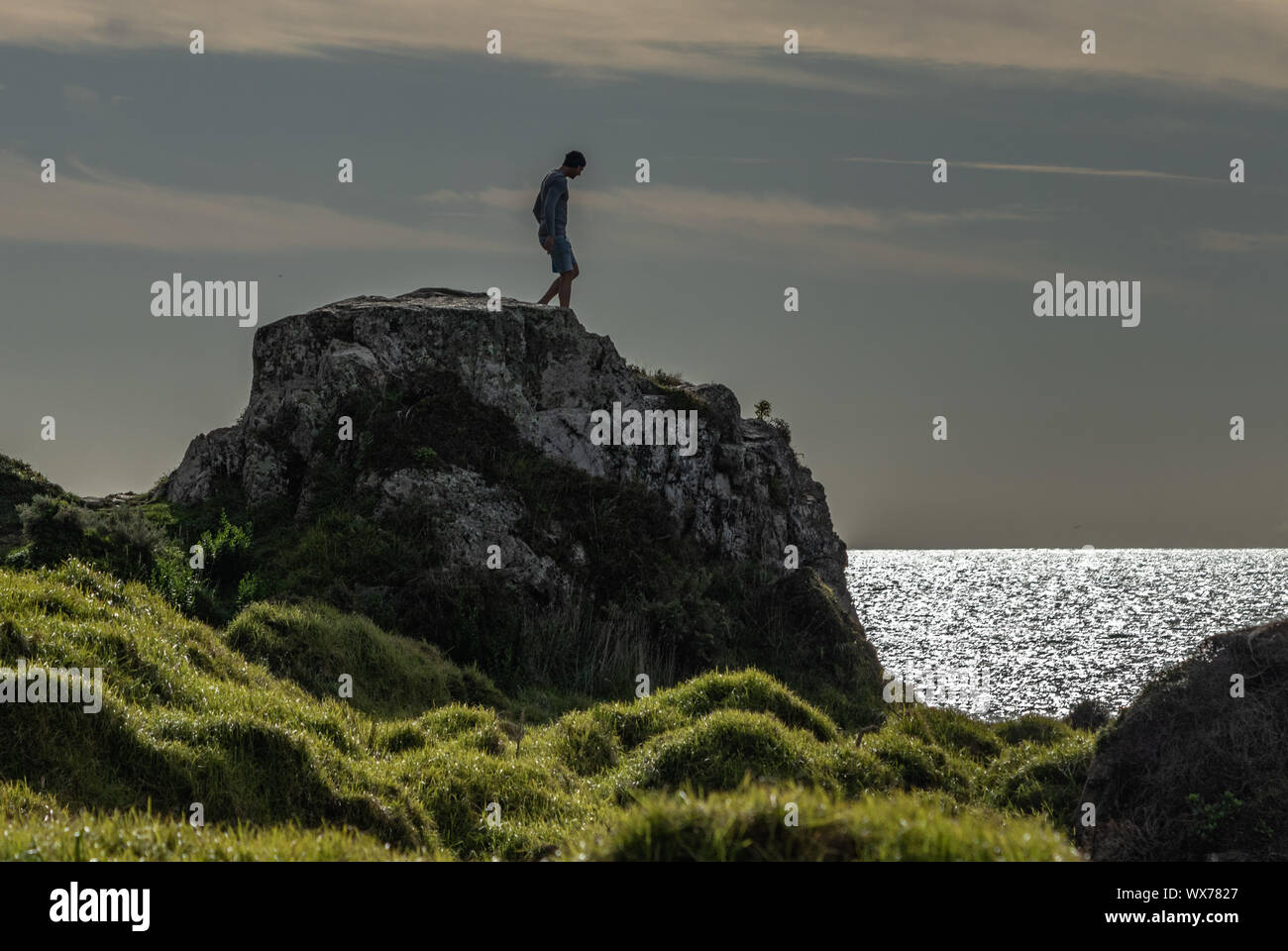 Man standing on rock overlooking ocean Stock Photo