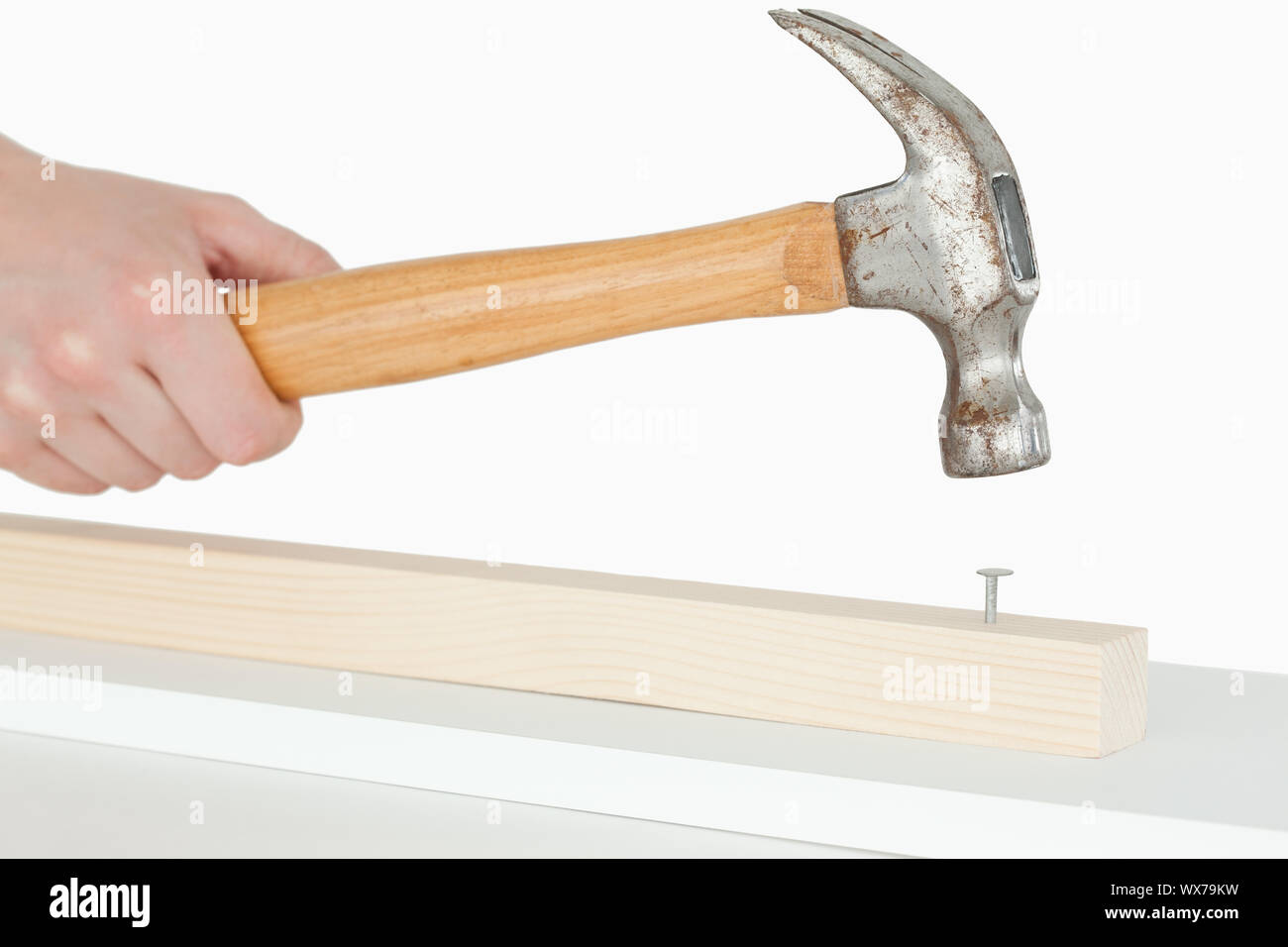 Hammer driving a nail into a wooden board against a white background Stock  Photo - Alamy