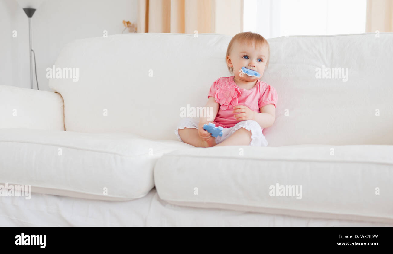 Lovely Blond Baby Playing With Puzzle Pieces While Sitting On A