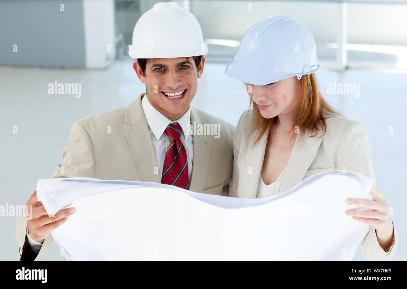 Two smiling engineers studying blueprints in a building site Stock Photo