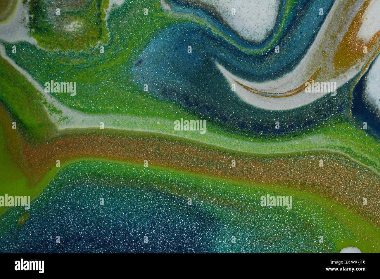 Neon green, glittery gold, glitter teal, white, and dark blue combine to create this abstract overhead view of islands in the ocean for backgrounds. Stock Photo
