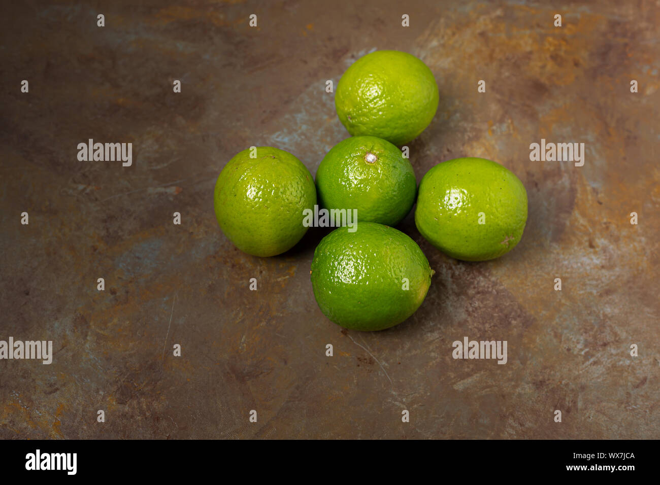 Freshly lime fruits on trendy rust background Stock Photo