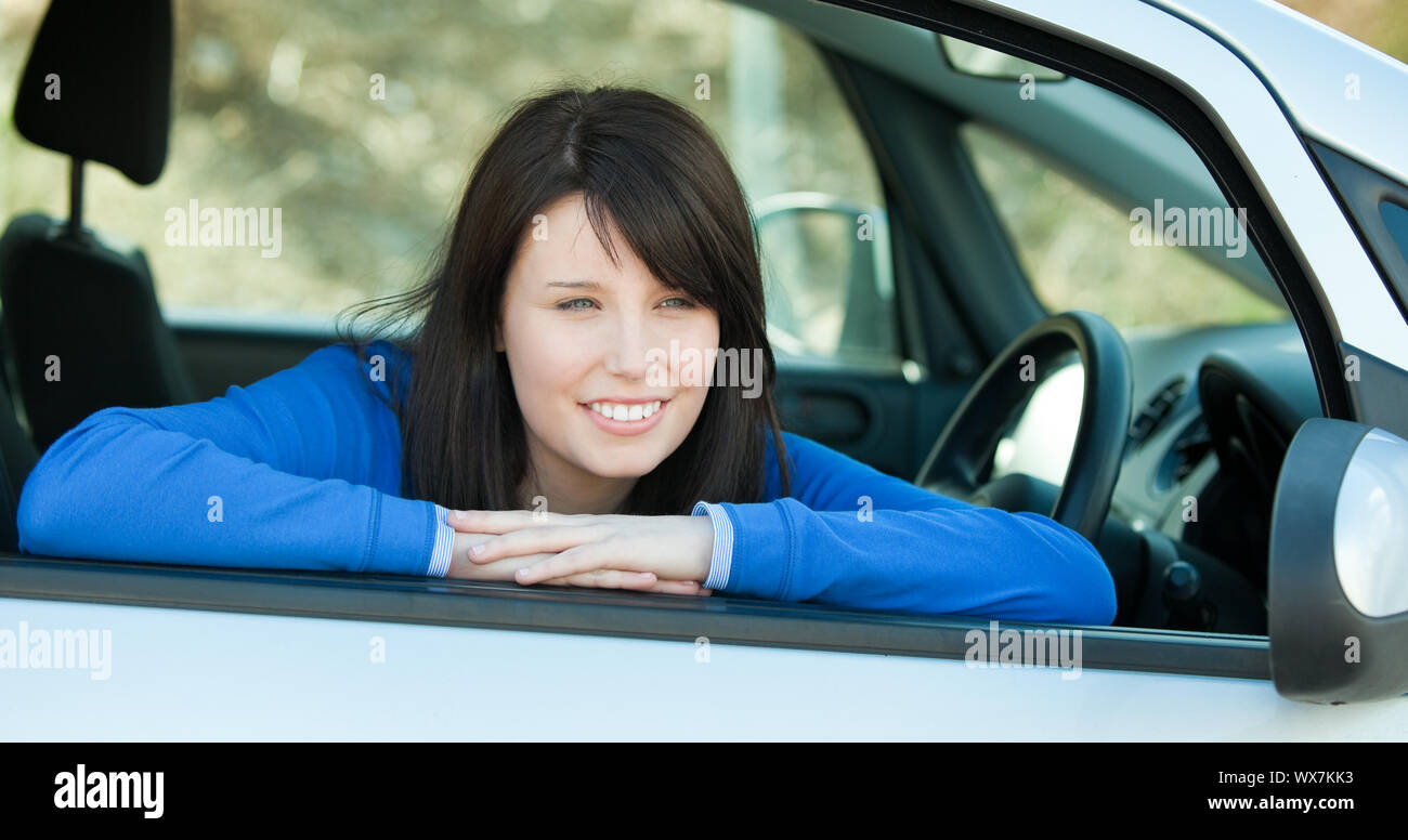 Charming teen girl smiling at the camera sitting in her car outdoor ...