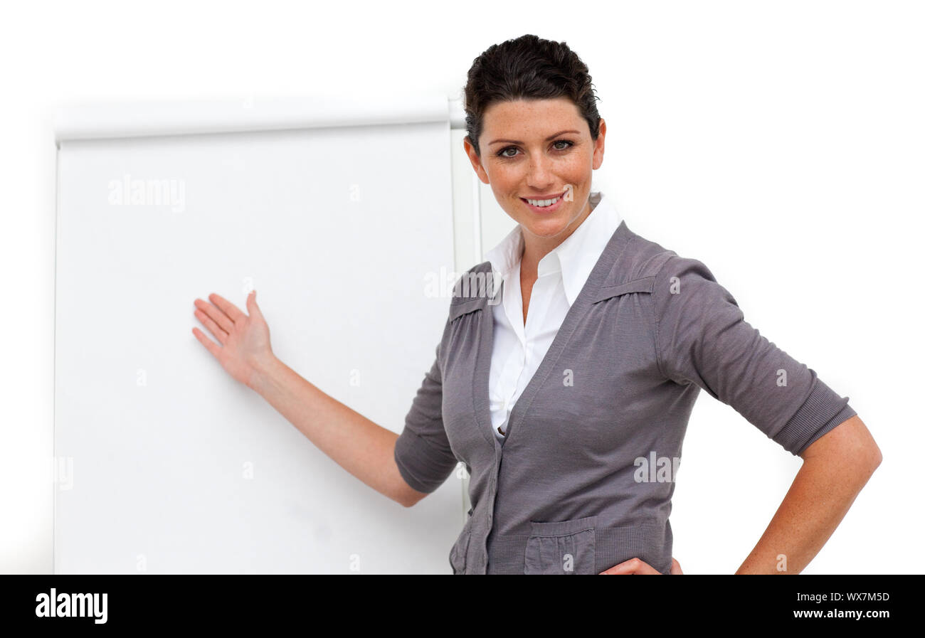 Confident female executive pointing at a board against a white ...