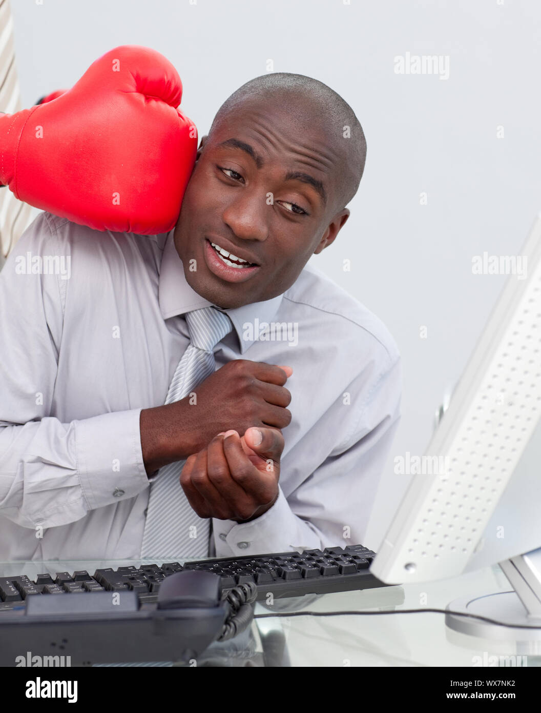 Ethnic businessman hit by a boxing glove in his office Stock Photo