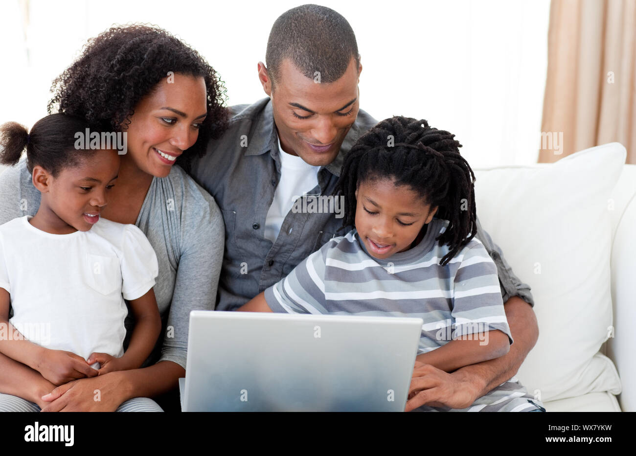 Happy Afro-American family using a laptop on the sofa Stock Photo - Alamy