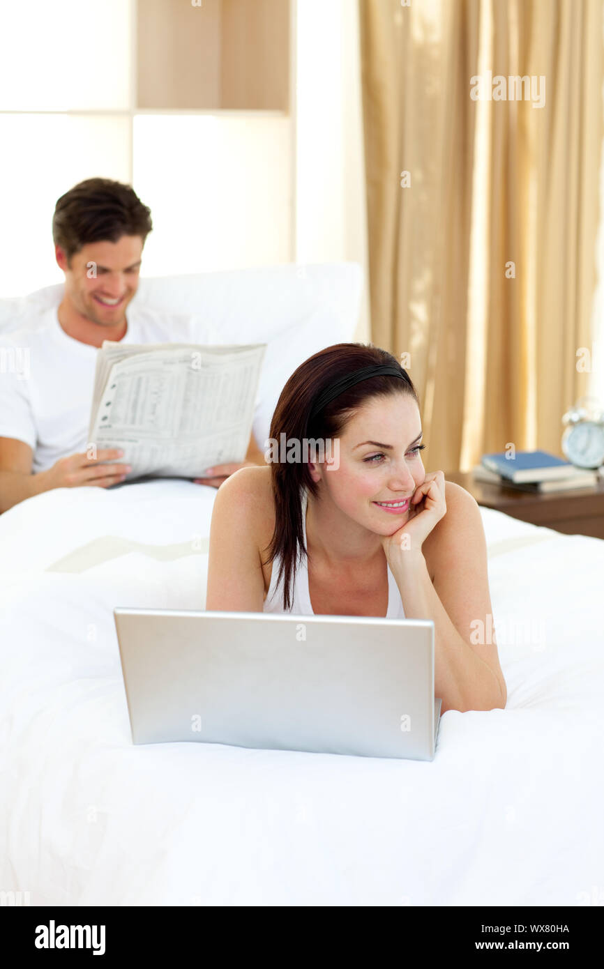 Beautiful woman using her laptop lying on her bed Stock Photo - Alamy