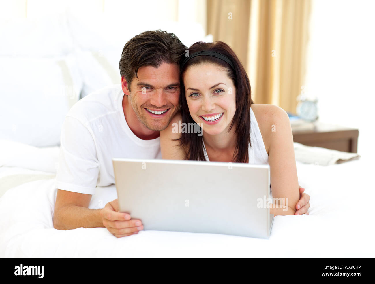 Loving couple using laptop lying on the bed Stock Photo - Alamy
